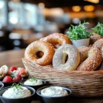 A selection of bagels with different cream cheese flavors in small bowls.