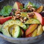 A colorful avocado and apple salad with walnuts and greens.