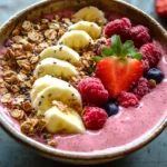 Smoothie bowl served with fresh fruit, granola, and chia seeds.